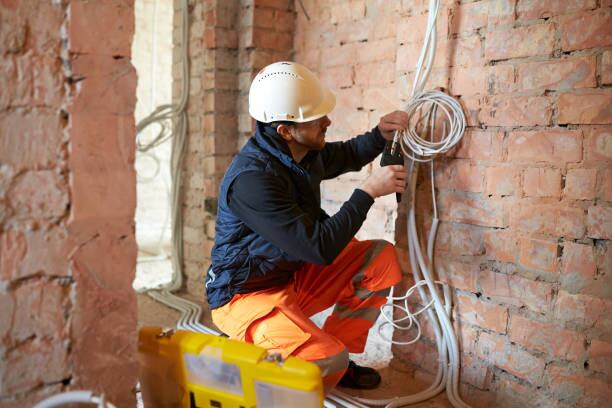 Male electrical contractor working with multiple cables during installation precess on construction site.