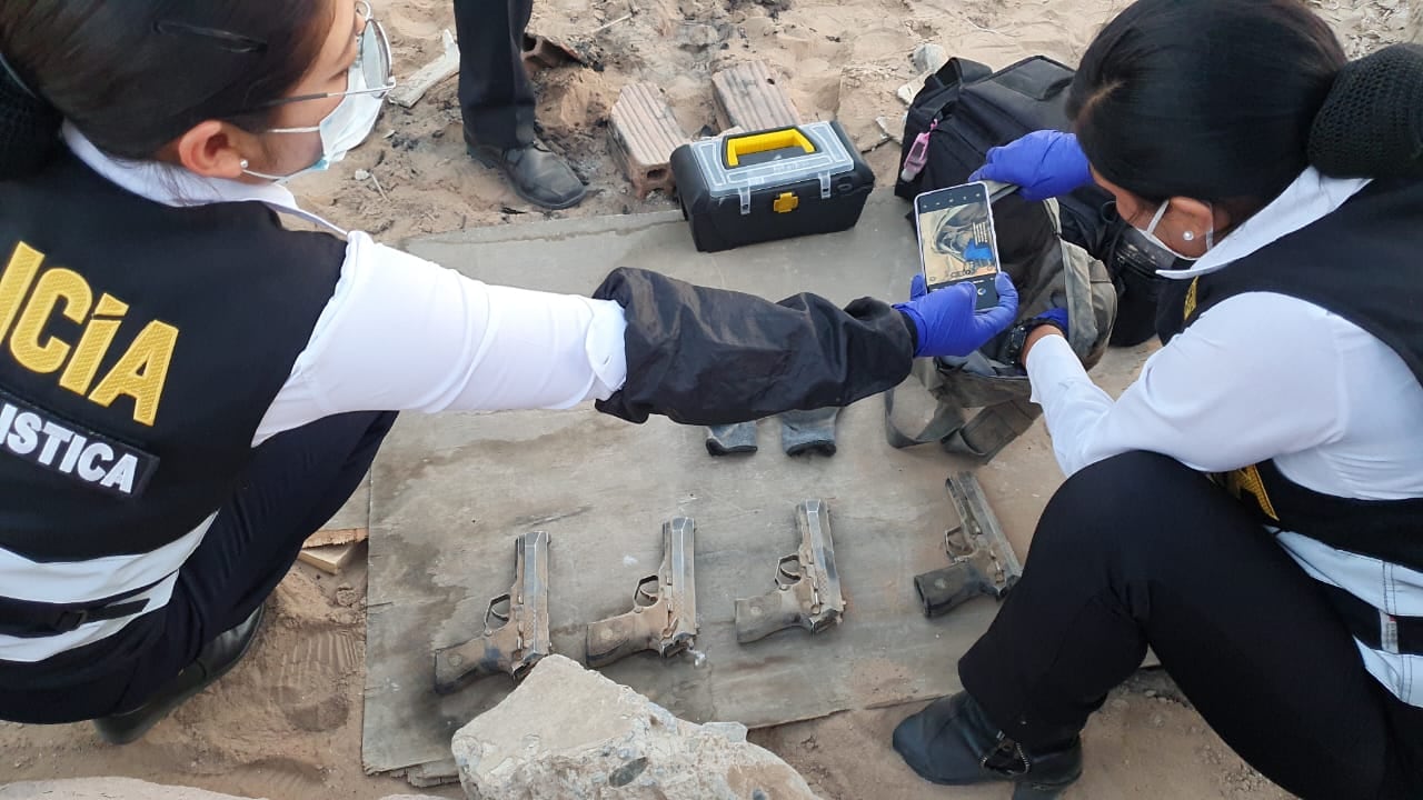 Agentes de la Oficina de Criminalística examinan las pistolas que estaban en un terreno descampado colindante al cuartel