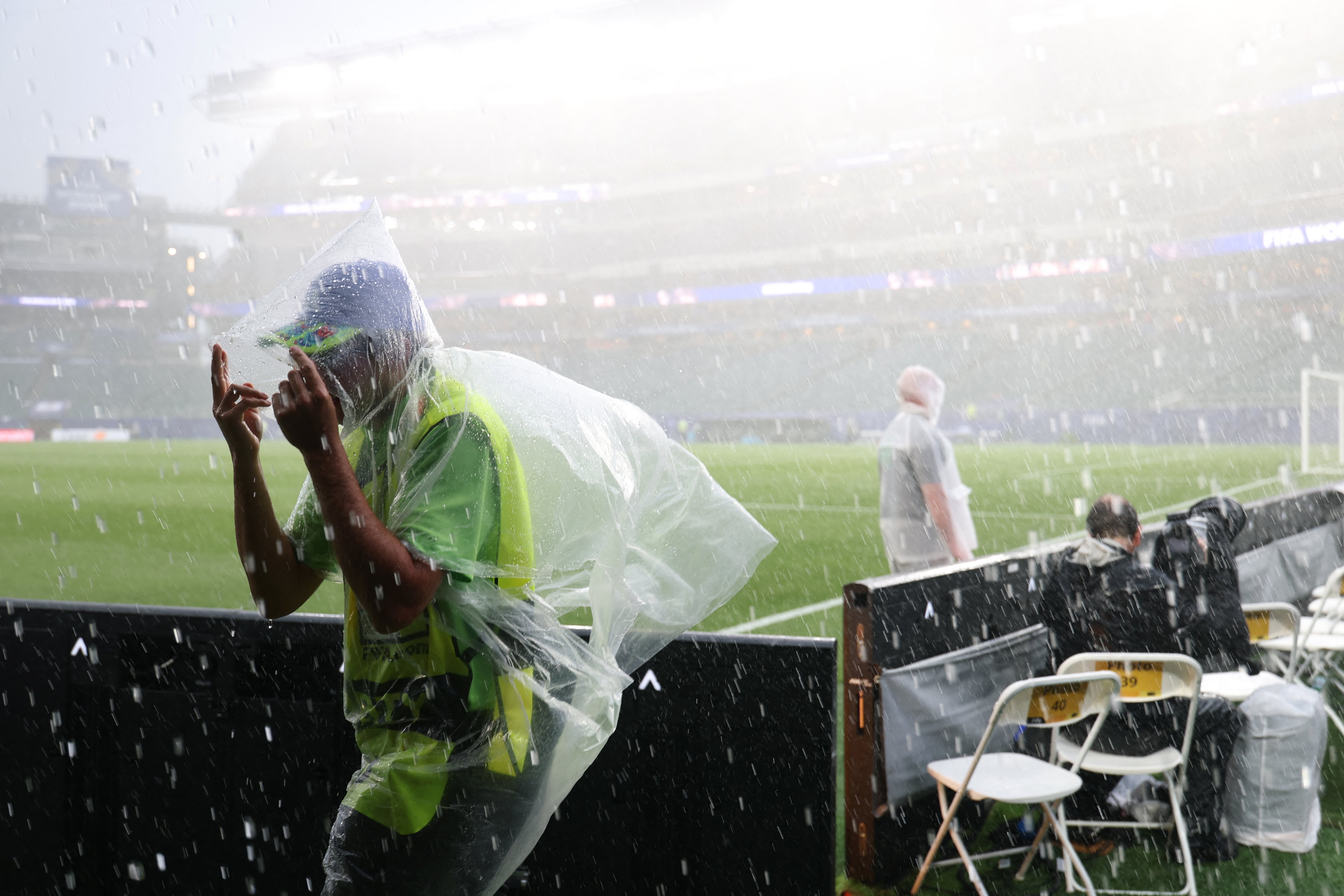 A photographer wears a raincoat as the 2026 World Cup Group I football match between France and Iraq is suspended due to adverse weather at the Philadelphia Stadium in Philadelphia on June 22, 2026. (Photo by FRANCK FIFE / AFP)