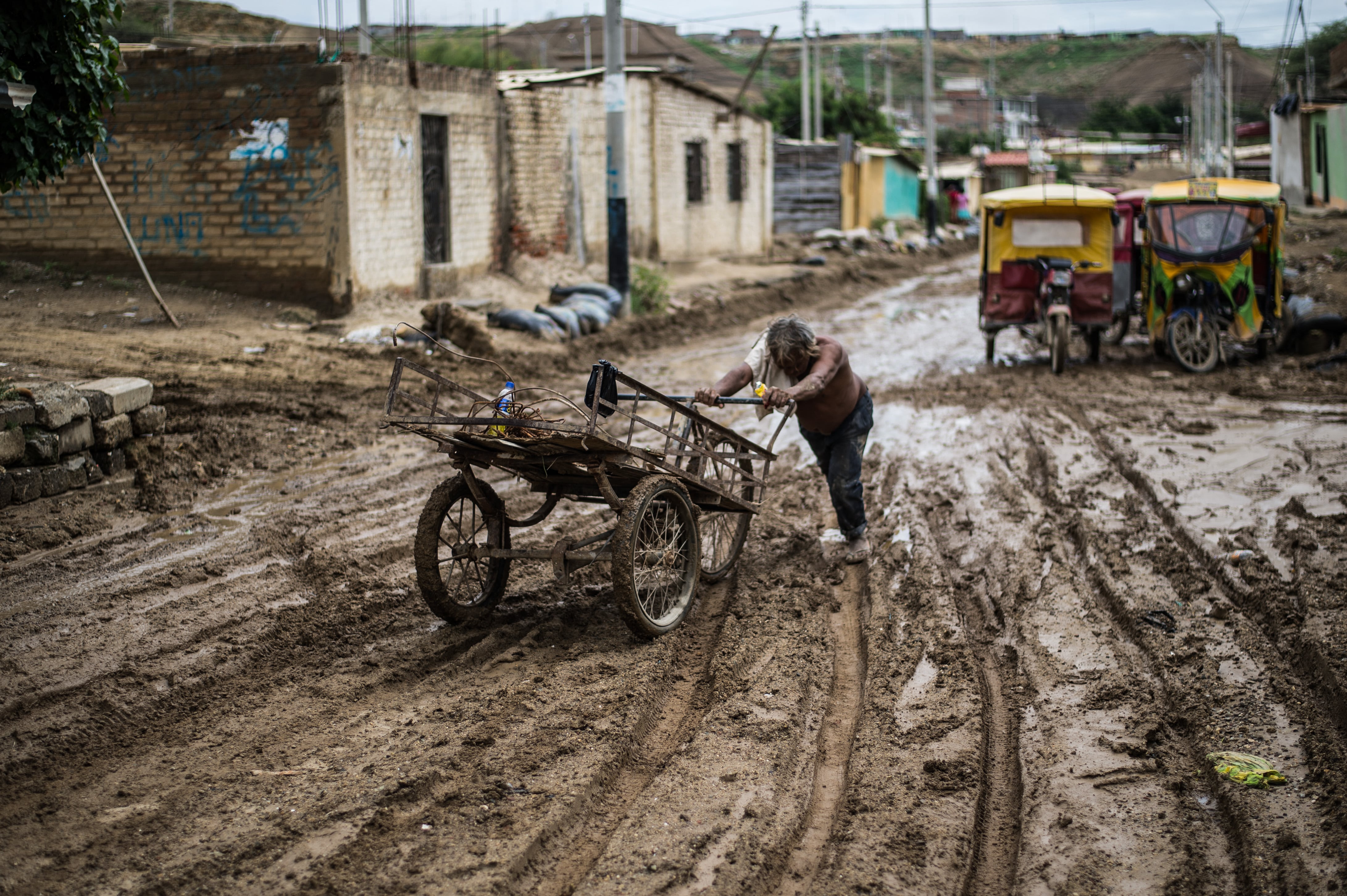 Un residente local empuja su carreta a través del lodo tras las inundaciones provocadas por las lluvias en la provincia de Paita, en Piura, al norte del Perú, el 24 de marzo de 2017, durante el fenómeno climático El Niño. (Foto de Ernesto BENAVIDES / AFP).