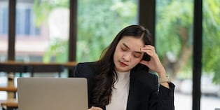 Beautiful Asian businesswoman using a laptop working in an office and depressed.