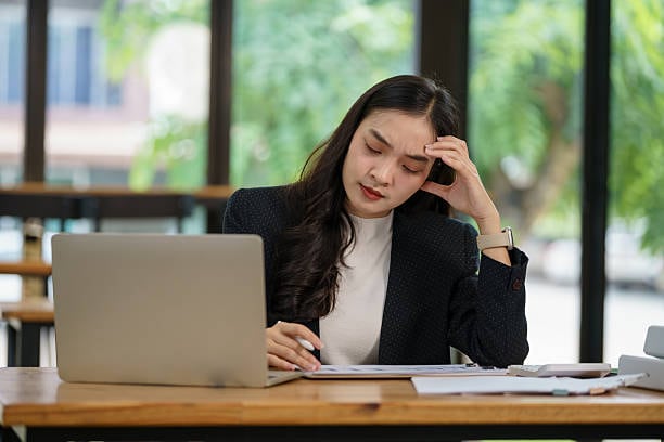 Beautiful Asian businesswoman using a laptop working in an office and depressed.