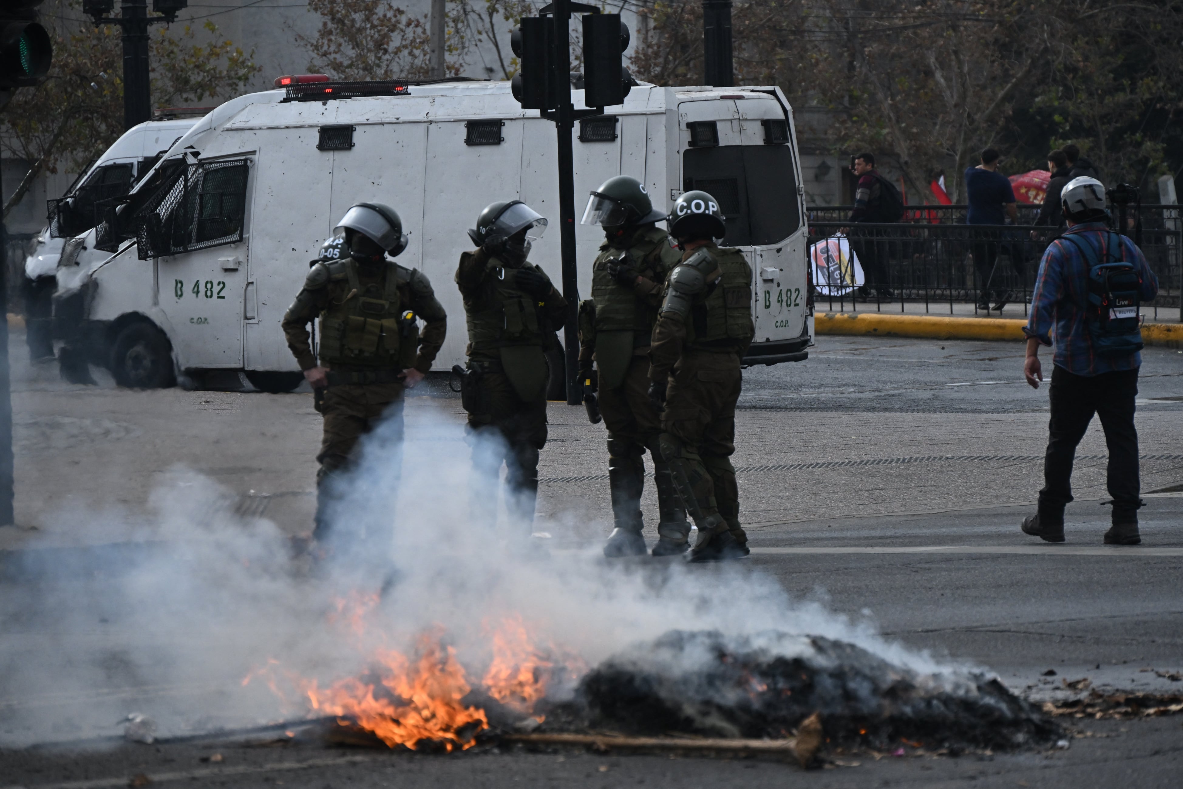 Riot police are seen near a fire set up by demonstrators following a students march against social cuts pushed through by Chile's President Jose Antonio Kast in Santiago, on June 3, 2026. (Photo by RODRIGO ARANGUA / AFP)