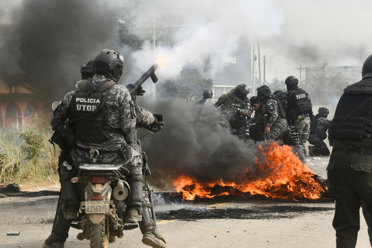 Agentes de policía se enfrentan a manifestantes antigubernamentales durante una operación para despejar un bloqueo de carretera en San Julián. (Rodrigo URZAGASTI / AFP)
