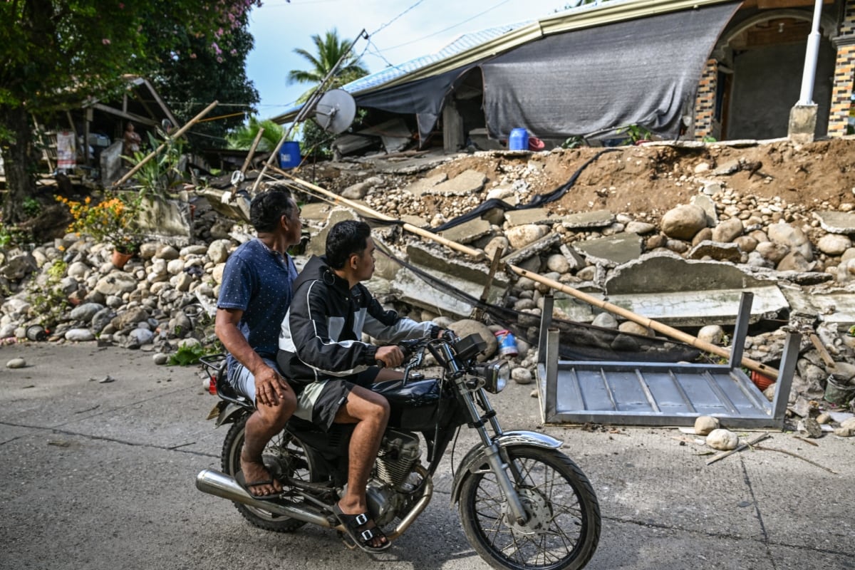 Hombres observan una casa dañada en Manay, después de que dos fuertes terremotos azotaran el sur de Filipinas. (Foto: AFP)