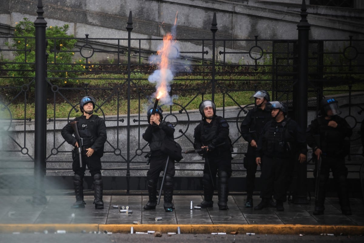 A riot police officer fires tear gas during a demonstration demanding that the government of Argentine President Javier Milei comply with a law updating funding for public universities, in Buenos Aires, on October 15, 2026. (Photo by Emiliano Lasalvia / AFP)