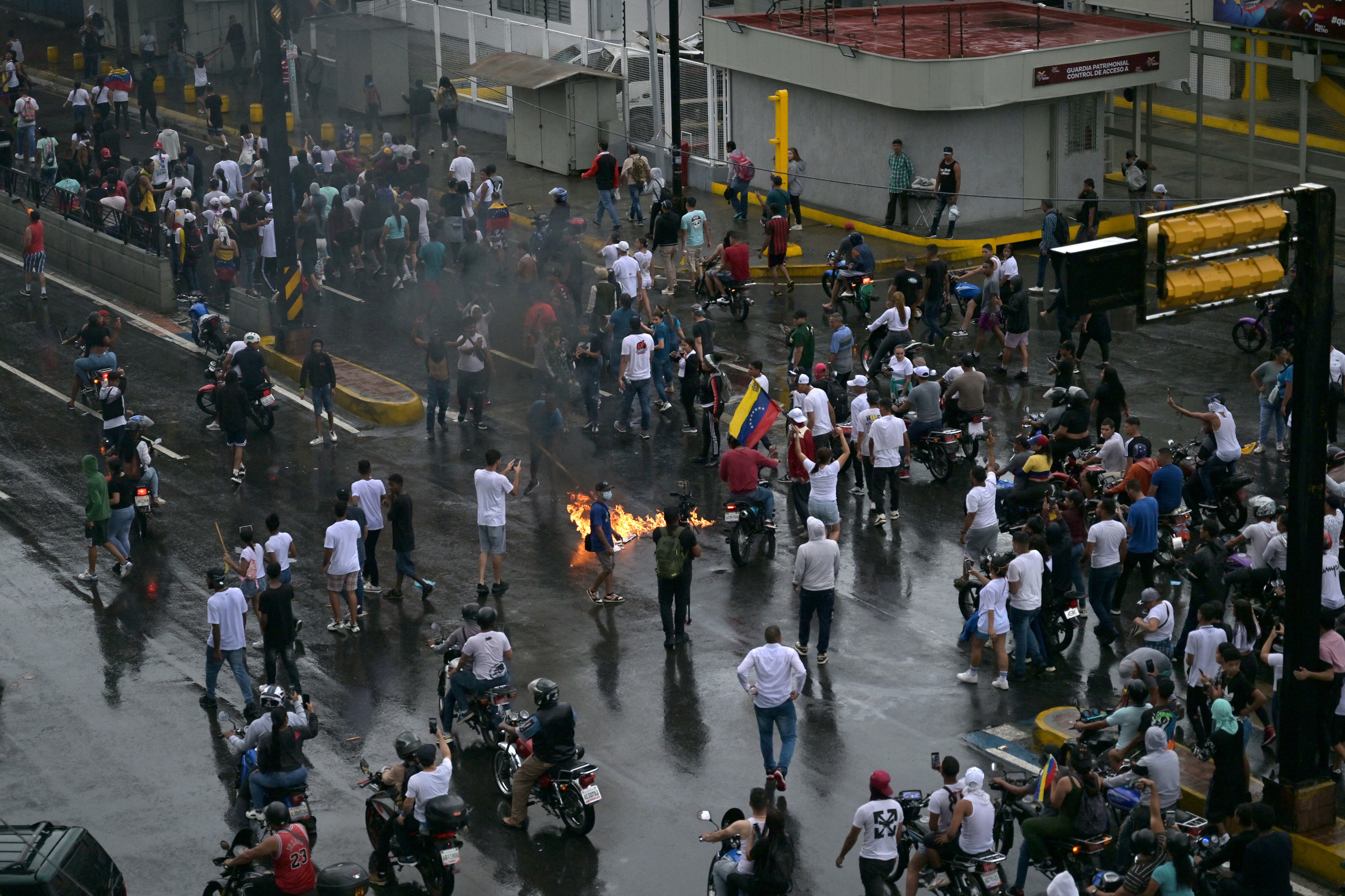 Los manifestantes queman carteles de campaña del presidente venezolano Nicolás Maduro durante una protesta en el barrio de Petare en Caracas el 29 de julio de 2024. (Foto de Juan BARRETO/AFP).