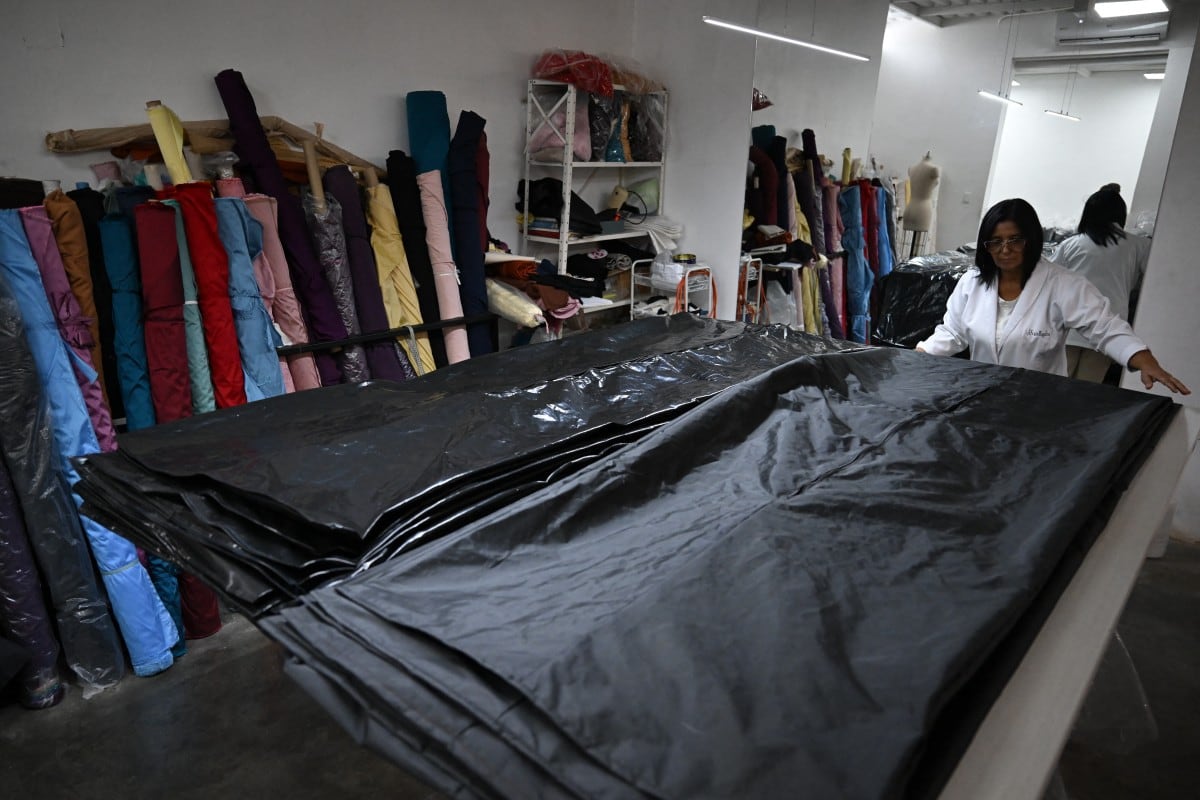 A seamstress works in the manufacture of body bags for the earthquake victims, at the ByEfrainMogollon workshop in Maracay, state of Aragua, Venezuela, on July 13, 2026. At a fashion workshop in Venezuela, the sewing machines set aside the brightly coloured threads used to make elegant dresses to sew body bags, which the creative director decided to donate to rescue workers, volunteers and relatives recovering bodies from the buildings that collapsed following the twin earthquakes measuring 7.2 and 7.5. (Photo by Raul ARBOLEDA / AFP)
