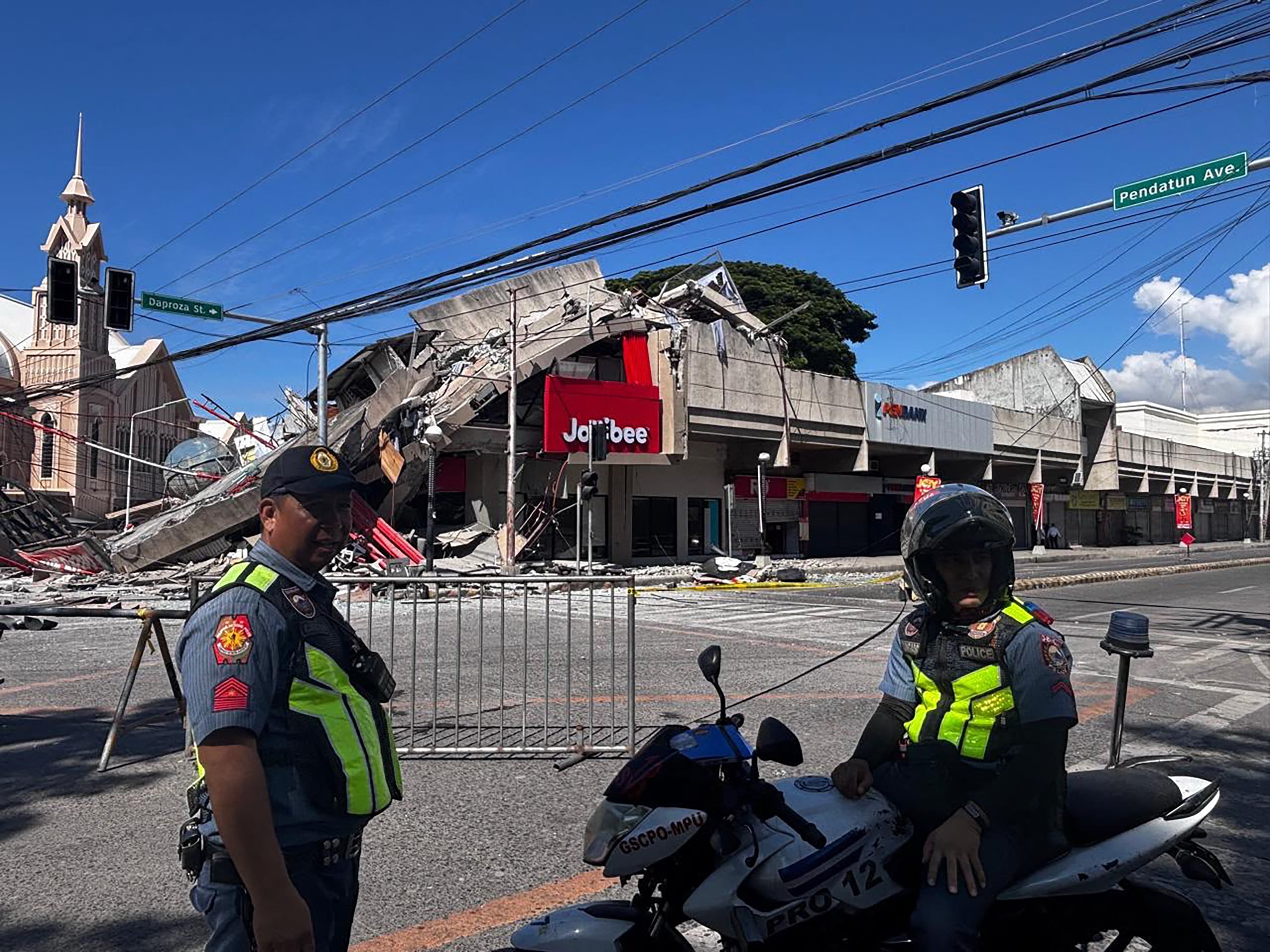 Policías se congregan frente a un restaurante Jollibee derrumbado tras el terremoto de magnitud 7,8 que sacudió la ciudad de General Santos, en Filipinas, el 8 de junio de 2026. (Foto de Edwin Espejo / AFP).