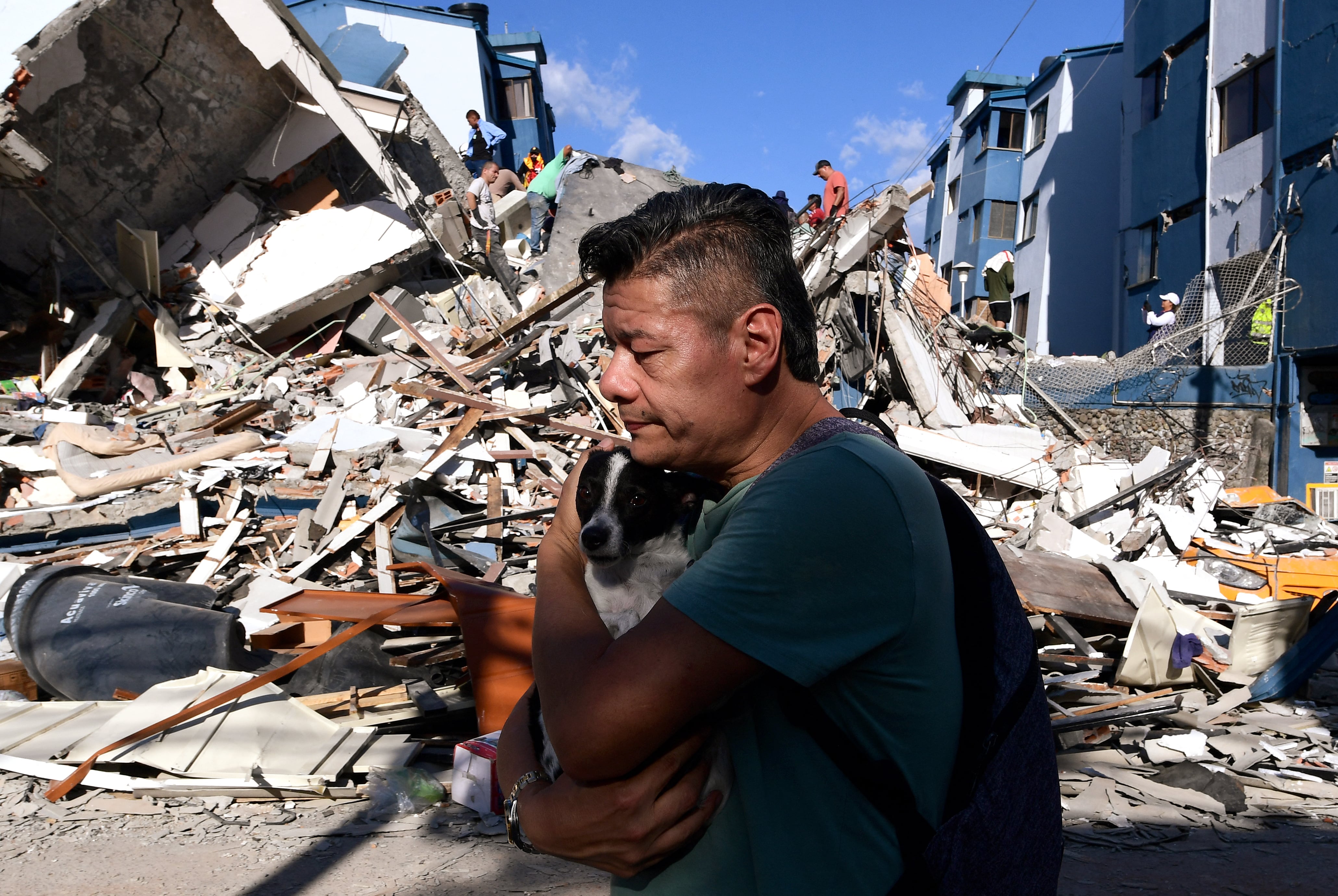 Un hombre lleva un perro mientras camina entre los escombros de un edificio derrumbado tras el terremoto en Pereira, Colombia, el 10 de agosto de 2026. (Foto de Jaime SALDARRIAGA / AFP).