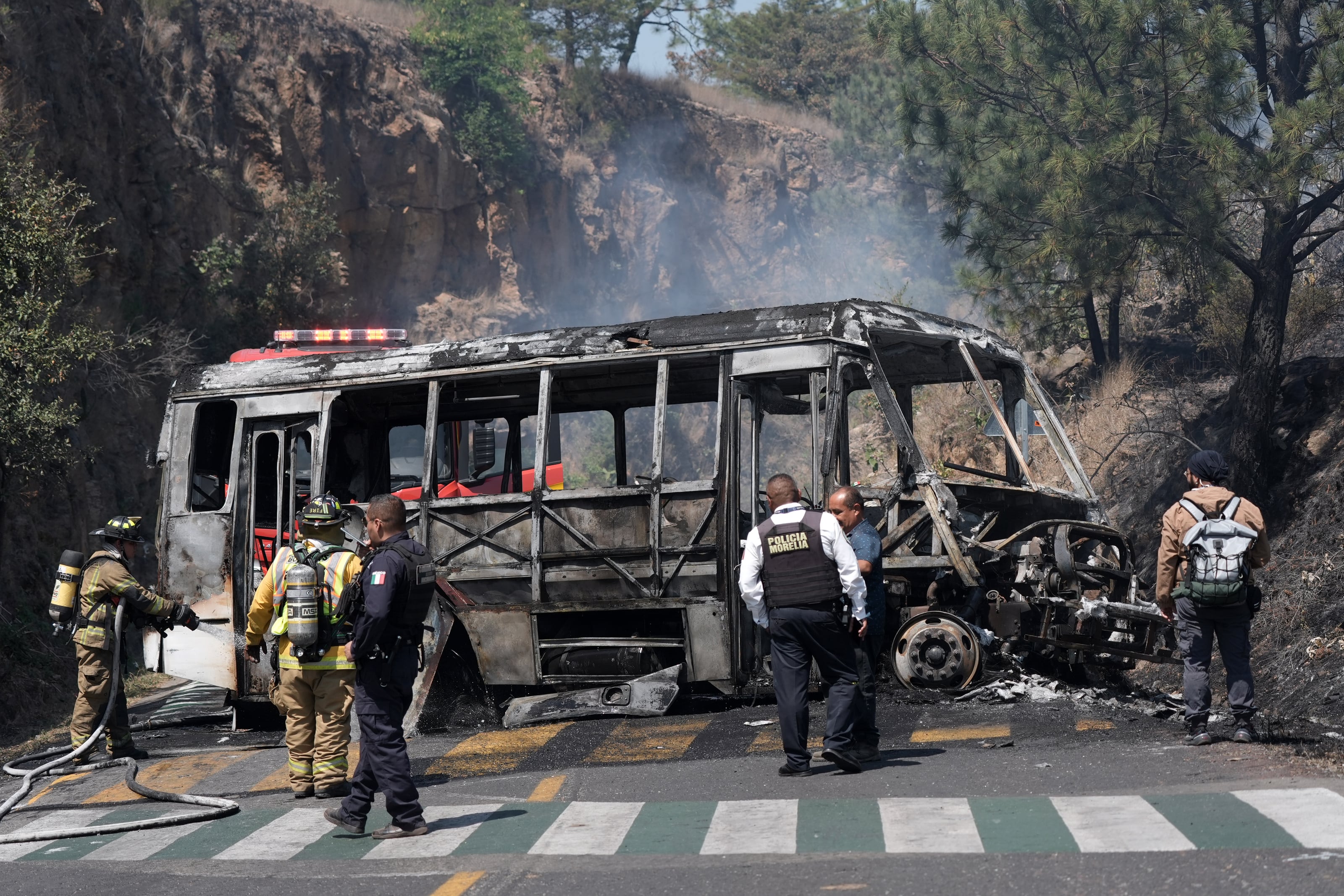 MEX5099. MORELIA (MÉXICO), 22/02/2026.- Bomberos e integrantes de la policía de Morelia trabajan en la zona donde fue incendiado un autobús por presuntos integrantes del crimen organizado este domingo, tras el abatimiento de Nemesio Oseguera Cervantes, alias El Mencho, líder del Cártel Jalisco Nueva Generación (CJNG), en Morelia (México). EFE/ Iván Villanueva