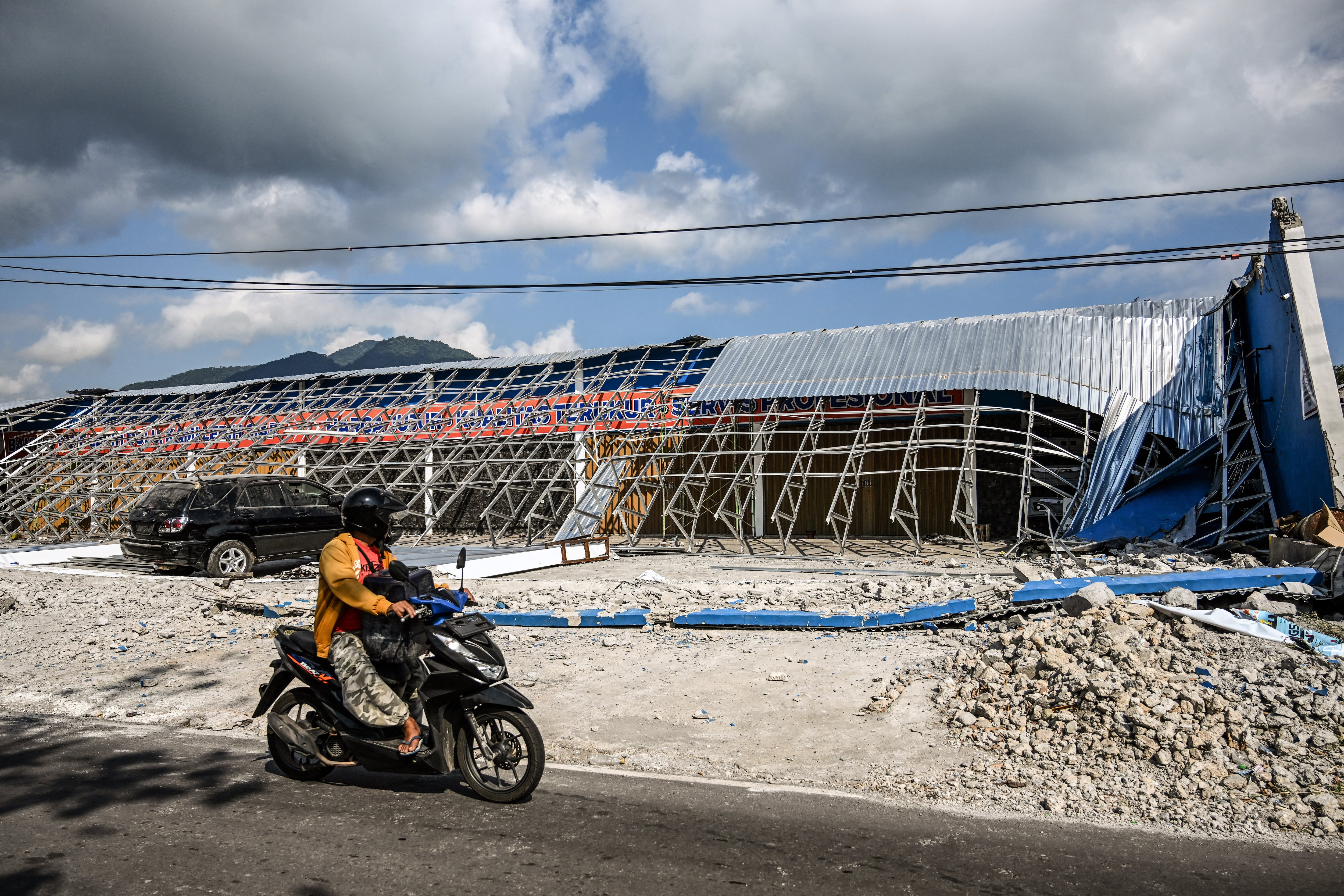 Un motociclista observa un edificio dañado tras el terremoto en Indonesia. (Foto de JUNI KRISWANTO / AFP).