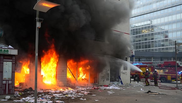 Los bomberos extinguen un incendio en una oficina del banco francés Credit Mutuel, tras los disturbios que estallaron después de una marcha de conmemoración de un conductor adolescente asesinado a tiros por un policía, en el suburbio parisino de Nanterre el 29 de junio de 2023. (Foto de Zakaria ABDELKAFI / AFP)