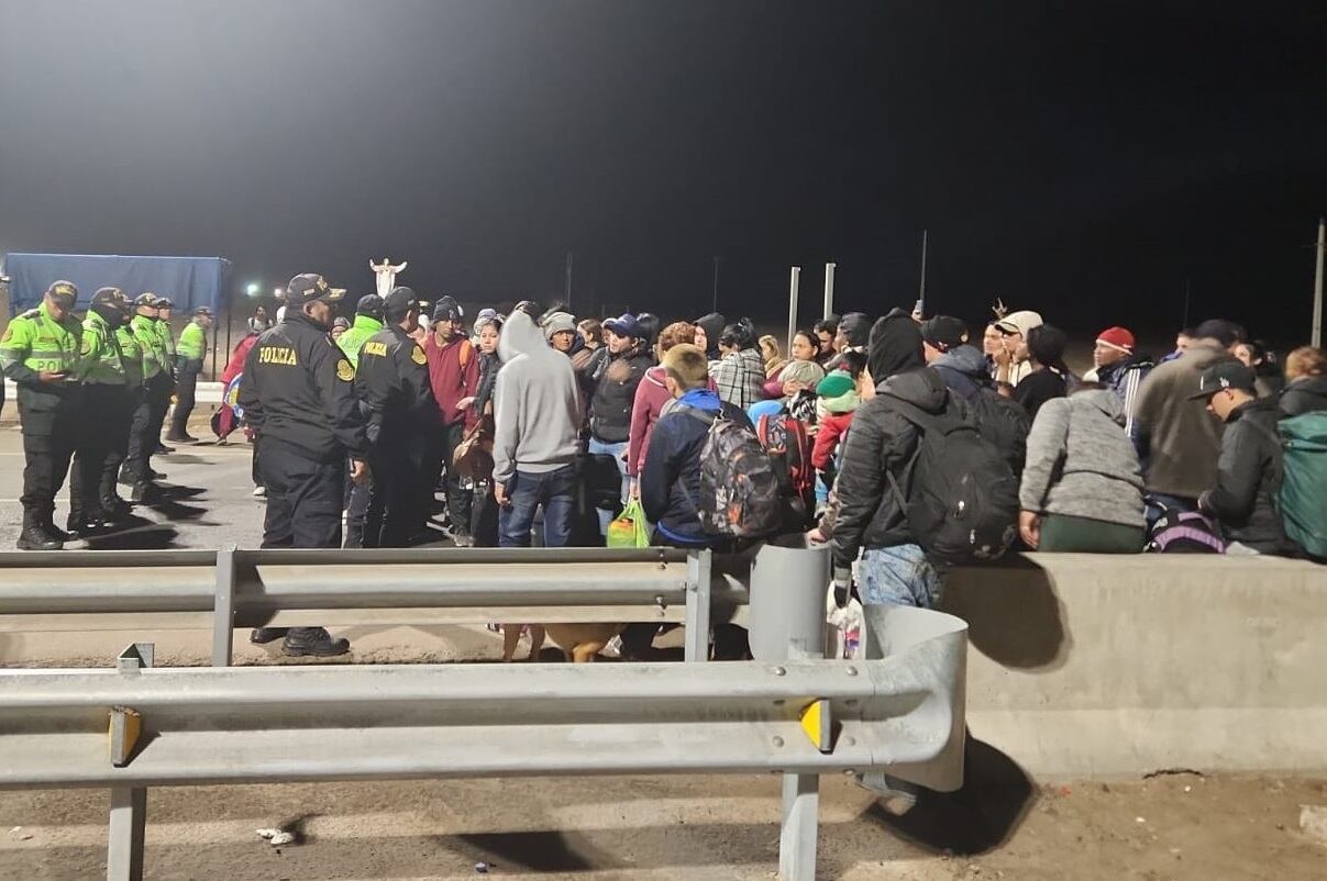 Haitianos, venezolanos y colombianos frente a barrera de policías en lado peruano