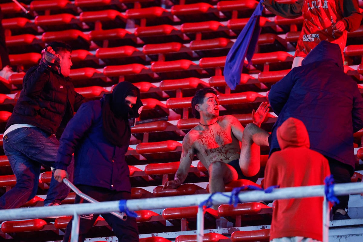 Hinchas se enfrentan en una tribuna en un partido entre Independiente y U de Chile. (Foto de Juan Ignacio Roncoroni / EFE)