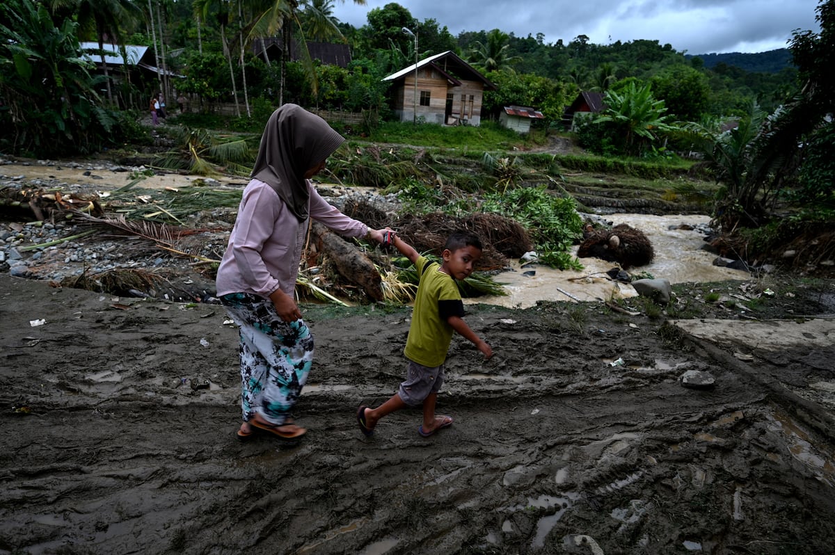 Una mujer y un niño caminan entre los escombros después de una inundación repentina en una aldea en Tangse, provincia de Aceh en Indonesia, el 30 de octubre de 2021. (Foto: CHAIDEER MAHYUDDIN / AFP)