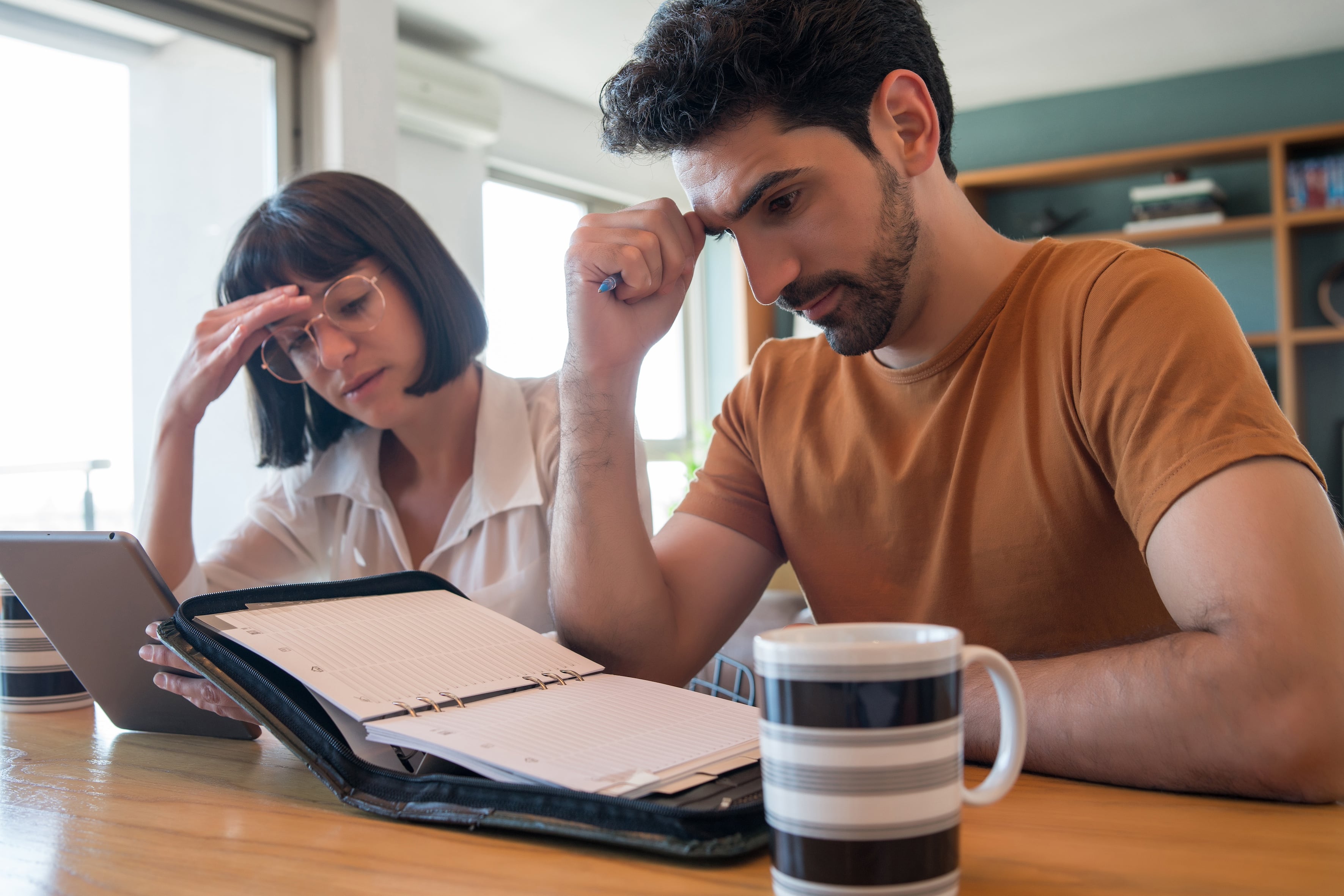 Portrait of young couple calculating and paying bills on digital tablet from home. Couple planning monthly budget.