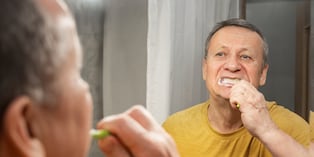 Brushing teeth with foam in mirror, caucasian adult male performing morning oral hygiene routine at bathroom sink. Man Brushing Teeth