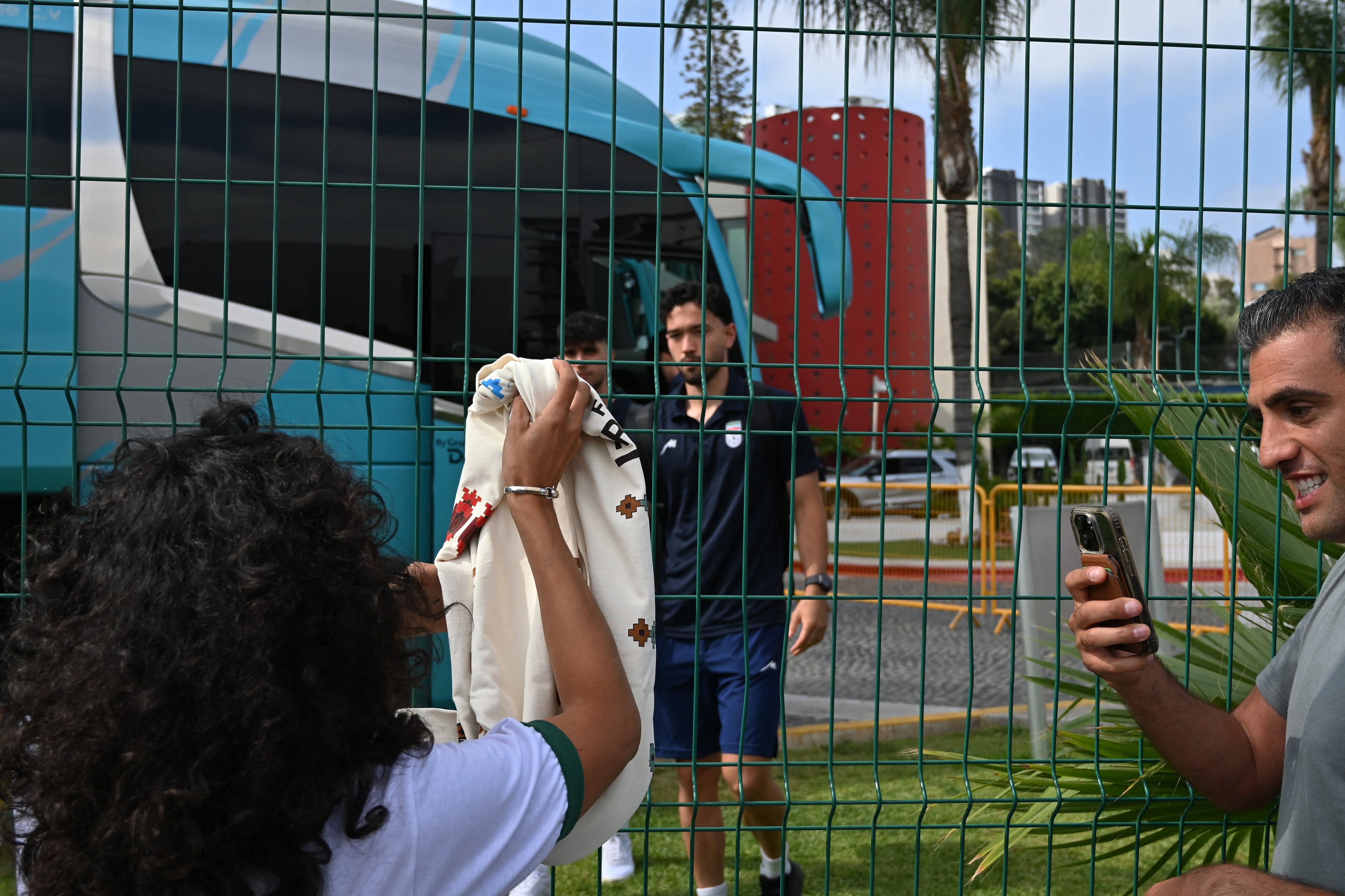 TIJUANA, MEXICO - JUNE 24: Yalda, a Tijuana-based Iranian citizen, who works as a painter, shows off t-shirts she produced for the Iranian National team before their leave from the Marriott Hotel to the Tijuana International Airport upon the team’s departure for Seattle, Washington, where it will play against Egypt on Friday in Tijuana, Mexico, on Wednesday, June 24, 2026, as part of the 2026 World Cup football tournament. (Carlos A. Moreno for Anadolu Images) Carlos Moreno / Anadolu (Photo by Carlos Moreno / Anadolu via AFP)