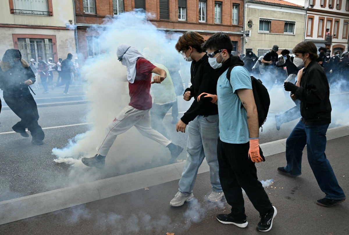 A protestor prepares to kick a smoking teargas canister as others look on during a demonstration of high-school students in Toulouse, southwestern France on October 13, 2026, as part of a nationwide high school mobilisation. France sees nationwide demonstrations on October 13 in support of students protesting poor classroom conditions for weeks, as authorities and participants remain wary of further violence. (Photo by Lionel BONAVENTURE / AFP)