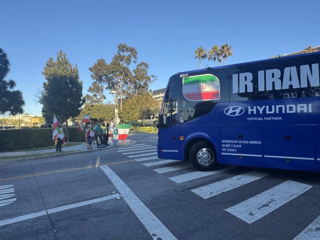LOS ANGELES, UNITED STATES - JUNE 20: Protesters gather outside the hotel hosting Iran’s national football team ahead of its 2026 FIFA World Cup Group G match against Belgium, waving Iran’s former lion-and-sun flag and U.S. flags, in Los Angeles, United States, on June 20, 2026. Bozhan Memis / Anadolu (Photo by Bozhan Memis / Anadolu via AFP)