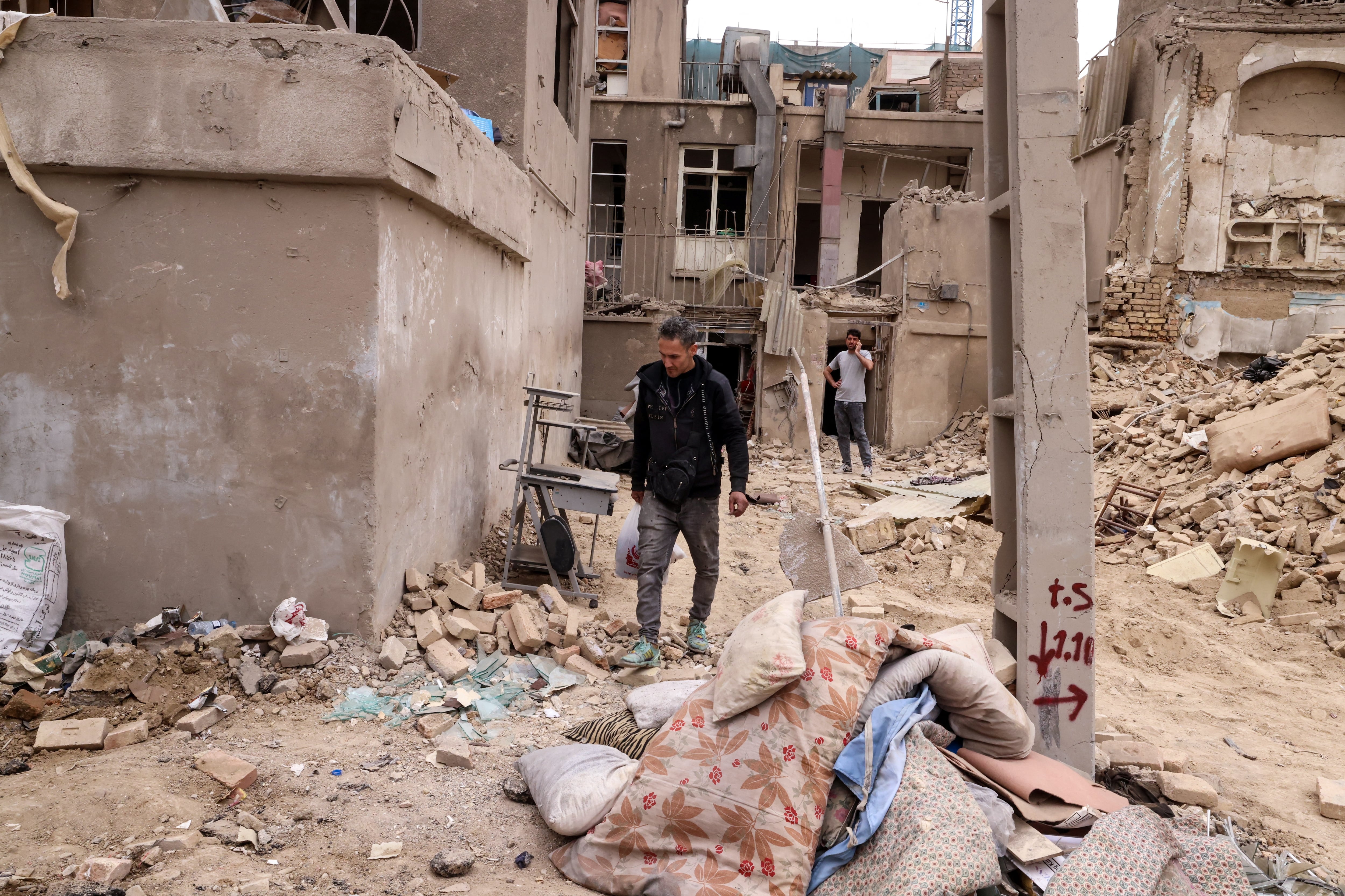 An Iranian collects his belongings from destroyed buildings following a military strike on the Iranian capital Tehran on March 15, 2026. Iran's Foreign Minister said in an interview published on March 15, that the war pitting his country against the United States and Israel will only end when Tehran can be certain it will not be restarted. On February 28, Israel and the United States launched strikes on Iran, killing its supreme leader Ayatollah and triggering a war that spread across the Middle East. (Photo by Atta KENARE / AFP) /