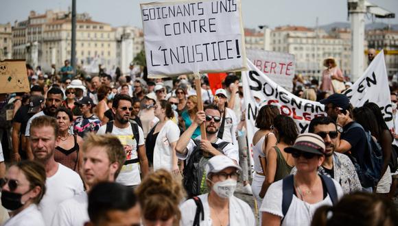 Un manifestante sostiene un cartel que dice "Trabajadores de la salud unidos contra la injusticia" durante una manifestación contra la vacunación obligatoria para ciertos trabajadores y el uso obligatorio del pase de salud convocado por el gobierno francés, en Marsella. (CLEMENT MAHOUDEAU / AFP)