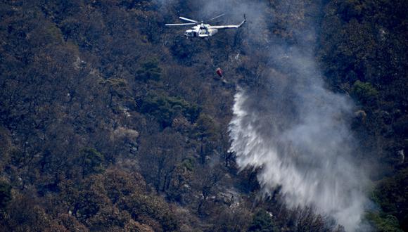 Un helicóptero de extinción de incendios de la Fuerza Aérea Mexicana arroja agua sobre un incendio forestal en el cerro Tepozteco, en Tepoztlán, estado de Morelos, México, el 23 de marzo de 2022. (Foto: Haaron Alvarez / AFP)