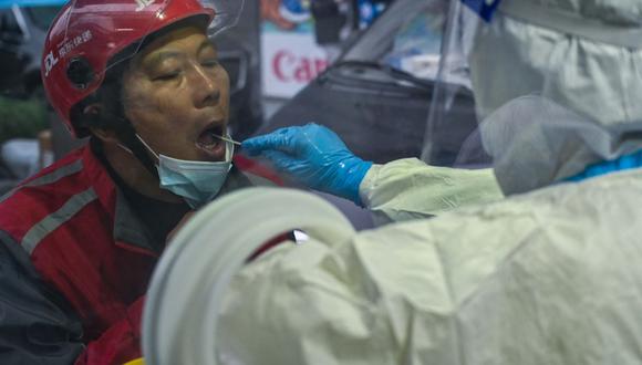 Un trabajador de la salud toma una muestra de hisopo de una mujer para detectar el coronavirus en el distrito de Huangpu, en Shanghai, China, el 8 de diciembre de 2022. (Héctor RETAMAL / AFP).