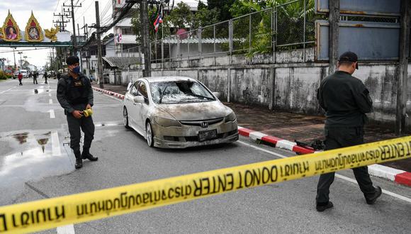 Los oficiales de policía se paran cerca de un automóvil parcialmente dañado, luego de que un coche bomba explotara frente a un alojamiento policial en la ciudad de Narathiwat, en el sur de Tailandia, el 22 de noviembre de 2022. (Foto de MADAREE THOLALA / AFP)