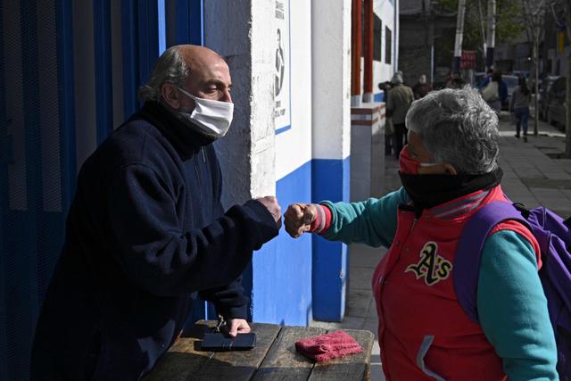 El sacerdote argentino Lorenzo De Vedia (izquierda) saluda a una mujer en la Villa 21 de Buenos Aires. (AFP / JUAN MABROMATA).