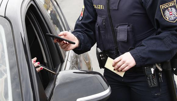 Un oficial de policía austriaco verifica el certificado de vacunación digital de un conductor en un teléfono inteligente durante un control de tráfico en Graz, Austria, el 15 de noviembre de 2021. (Foto: GERT EGGENBERGER / APA / AFP)