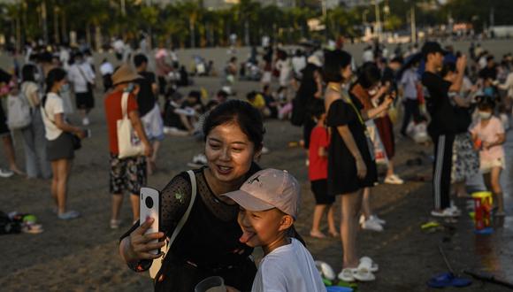 Una mujer y un niño posan para selfies en la playa de Baicheng en Xiamen, en la provincia de Fujian, en el sur de China, el 24 de julio de 2022. (Foto de Jade Gao / AFP)
