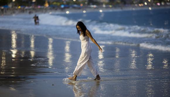 Una mujer camina por la orilla de la playa de Copacabana en vísperas de Año Nuevo, en Río de Janeiro, Brasil, el 31 de diciembre de 2021. (Foto de Daniel RAMALHO / AFP)