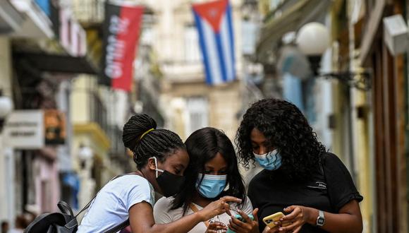 Mujeres usan sus teléfonos en una calle de La Habana (Cuba), el 14 de julio de 2021. (YAMIL LAGE / AFP).