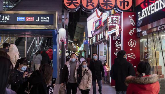 Personas con máscaras faciales caminan por una calle en Wuhan el 10 de enero de 2021, la víspera del primer aniversario de que China confirmó su primera muerte por el coronavirus Covid-19. (Foto de NICOLAS ASFOURI / AFP)