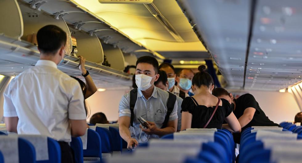 Los pasajeros, que usan mascarillas como medida preventiva contra el coronavirus, abordan un vuelo a la ciudad china central de Wuhan, en el Aeropuerto Internacional de Pudong en Shanghái. Imagen del 14 de julio de 2020. (AFP / Hector RETAMAL)