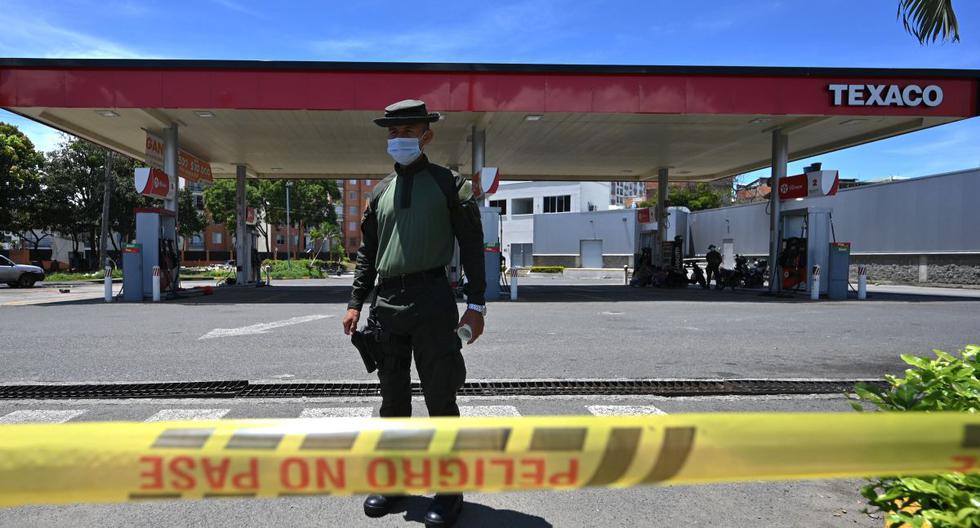 Un policía hace guardia en una gasolinera para evitar una posible destrucción en el marco de las protestas contra el gobierno del presidente Iván Duque, en Cali, Colombia, el 7 de mayo de 2021. (Luis ROBAYO / AFP).