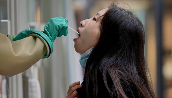 Un trabajador de la salud toma una muestra de un hisopo para detectar el Covid-19 durante una prueba masiva en un centro de pruebas improvisado en el este de China. (Foto: Noel Celis / AFP)