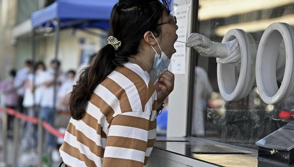 Un trabajador de la salud toma una muestra de hisopo de una mujer para realizarle la prueba del coronavirus Covid-19 en un sitio de recolección de hisopos en Beijing el 6 de julio de 2022. (Foto de Noel Celis / AFP)
