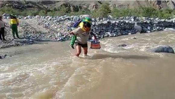 Profesor Ángel Carrasco carga a estudiantes en el hombre para cruzar el rio San Juan