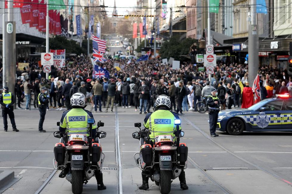La policía observa mientras los manifestantes participan en un mitin en Melbourne, mientras decenas de activistas anti-bloqueo y anti-vacunación se reunieron para manifestarse en las dos ciudades más grandes de Australia. (Foto de CON CHRONIS / AFP)